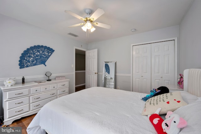 bedroom with dark wood-type flooring, visible vents, a closet, and ceiling fan