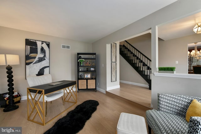 office area with wood finished floors, visible vents, baseboards, and an inviting chandelier