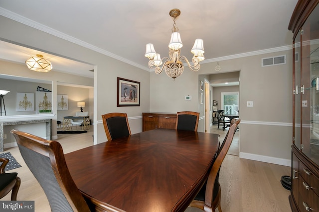 dining room with light wood finished floors, visible vents, crown molding, baseboards, and a notable chandelier