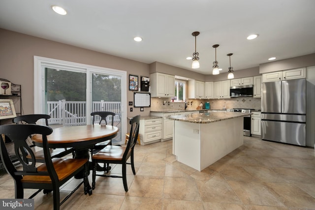 kitchen featuring recessed lighting, light stone counters, backsplash, a kitchen island, and appliances with stainless steel finishes
