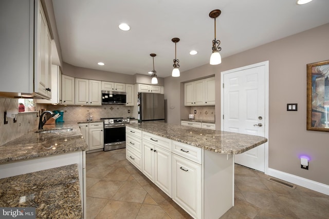 kitchen with a sink, stone counters, appliances with stainless steel finishes, visible vents, and recessed lighting