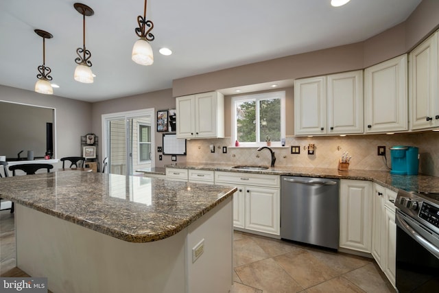 kitchen featuring dark stone countertops, a sink, decorative backsplash, stainless steel appliances, and decorative light fixtures