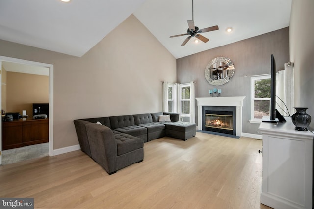 living room with a fireplace with flush hearth, ceiling fan, high vaulted ceiling, and light wood-type flooring
