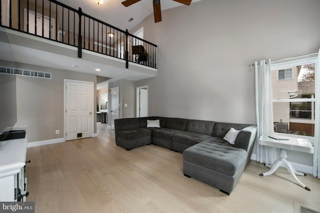 living room featuring a towering ceiling, a ceiling fan, wood finished floors, and baseboards