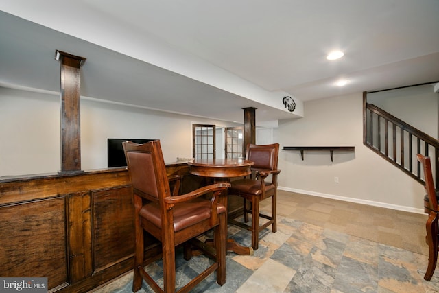 dining space featuring a dry bar, baseboards, recessed lighting, stone finish floor, and stairs