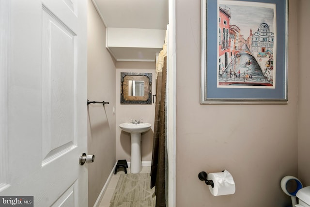 bathroom with baseboards, toilet, a sink, and tile patterned floors