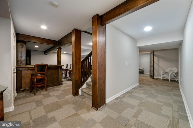 interior space with stairway, a dry bar, baseboards, and light colored carpet