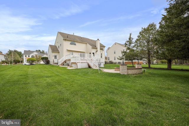back of house featuring a wooden deck, an outdoor fire pit, a yard, and stairs