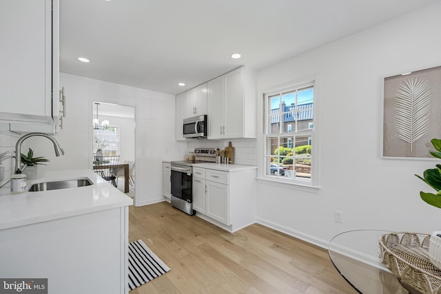 kitchen with plenty of natural light, stainless steel appliances, light wood finished floors, and a sink