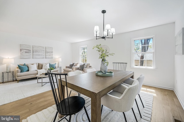 dining space with light wood-style flooring, baseboards, and a notable chandelier