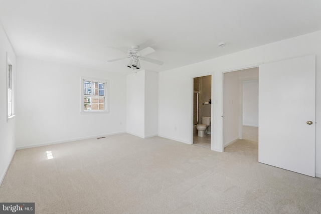 unfurnished bedroom with light carpet, baseboards, connected bathroom, and ceiling fan