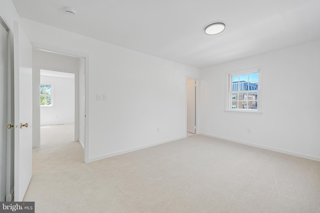 empty room featuring light colored carpet and baseboards