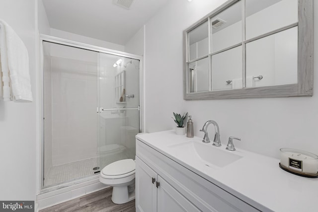 full bath featuring a shower stall, toilet, vanity, and wood finished floors