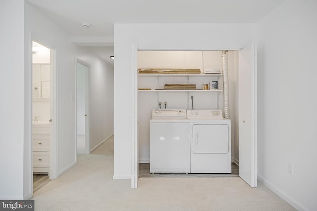 laundry area featuring baseboards, washing machine and clothes dryer, light colored carpet, and laundry area