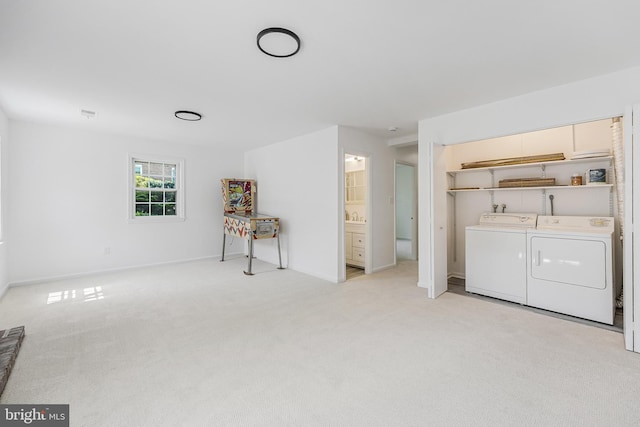 washroom with independent washer and dryer, baseboards, light carpet, and laundry area