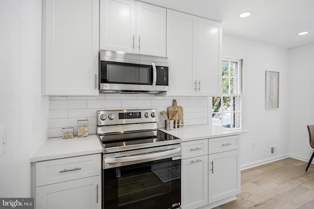 kitchen with tasteful backsplash, light wood finished floors, light countertops, white cabinets, and appliances with stainless steel finishes
