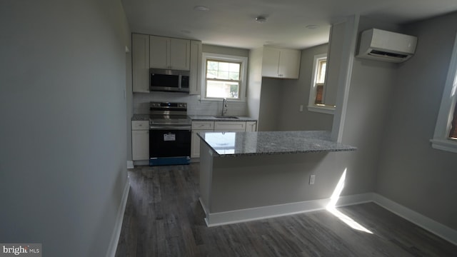 3220 Byberry Rd, Philadelphia, PA 19154 - kitchen with stainless steel appliances, a wall mounted air conditioner, dark wood finished floors, white cabinets, and light stone countertops
