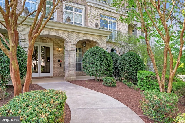 view of exterior entry featuring brick siding and french doors