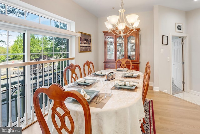 dining area with light wood-type flooring, baseboards, and a chandelier