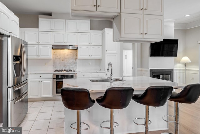 kitchen featuring under cabinet range hood, white cabinets, appliances with stainless steel finishes, and a sink