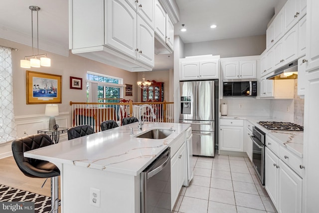 kitchen with a kitchen bar, a chandelier, a sink, appliances with stainless steel finishes, and backsplash