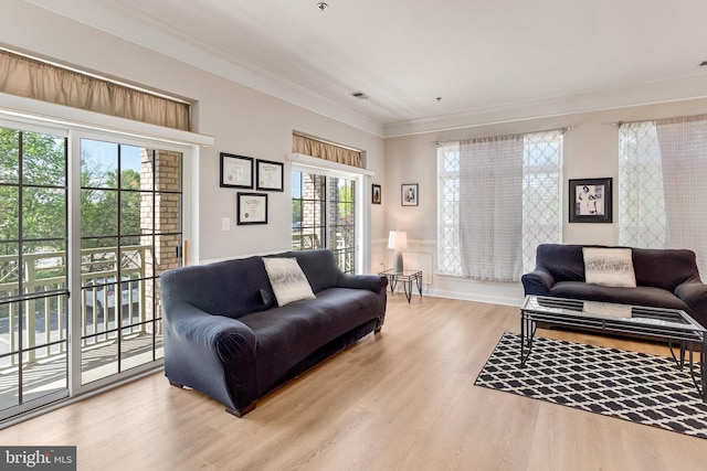 living area with visible vents, ornamental molding, and wood finished floors