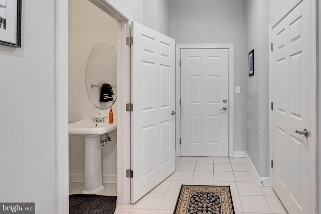 interior space with light tile patterned floors, baseboards, and a sink