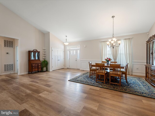 dining room featuring visible vents, an inviting chandelier, light wood-style floors, and high vaulted ceiling