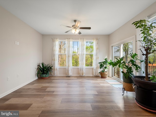 interior space featuring baseboards, wood finished floors, and a ceiling fan