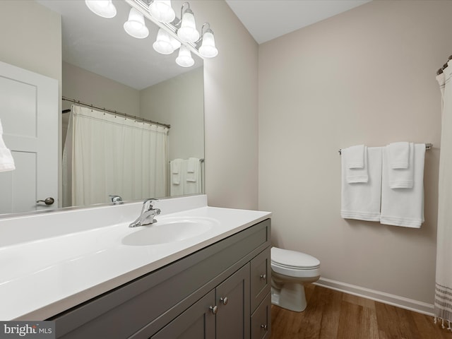 full bathroom featuring wood finished floors, toilet, vanity, and baseboards