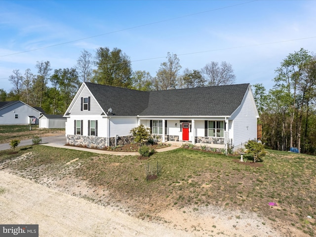 view of front of home with roof with shingles, a porch, a front lawn, and stone siding