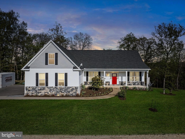 view of front facade featuring a porch, a front yard, stone siding, and a shingled roof