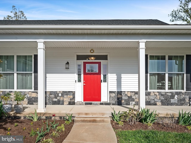 entrance to property with a porch and stone siding