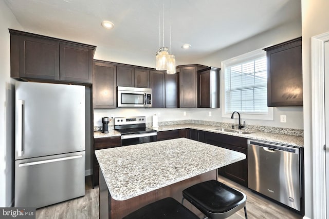 kitchen featuring dark brown cabinetry, light wood-type flooring, appliances with stainless steel finishes, and a sink