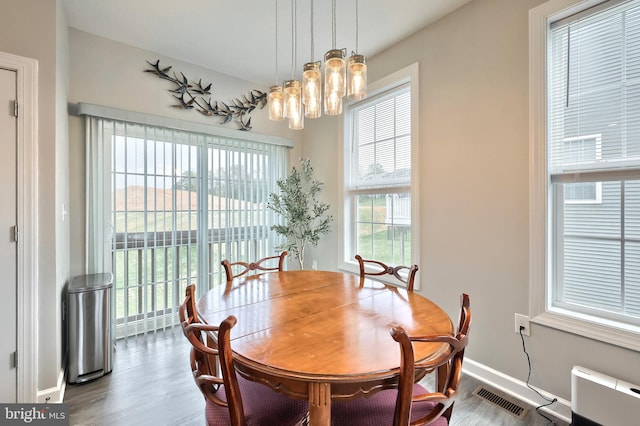 dining space with wood finished floors, a chandelier, radiator heating unit, baseboards, and visible vents