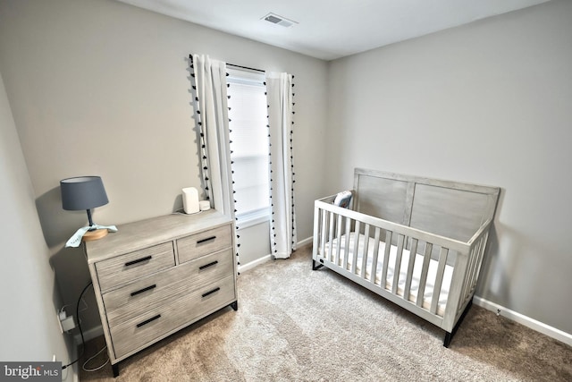bedroom with visible vents, light carpet, baseboards, and a crib