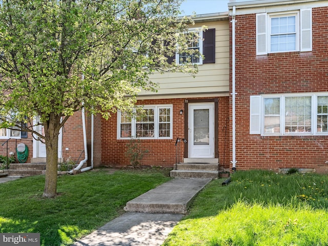 view of property featuring brick siding and a front yard