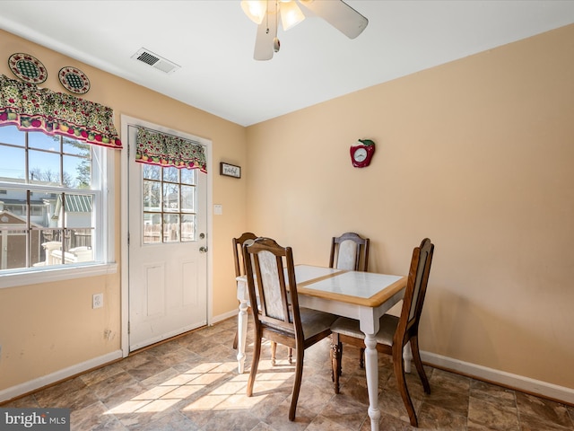 dining area featuring stone finish floor, visible vents, a ceiling fan, and baseboards