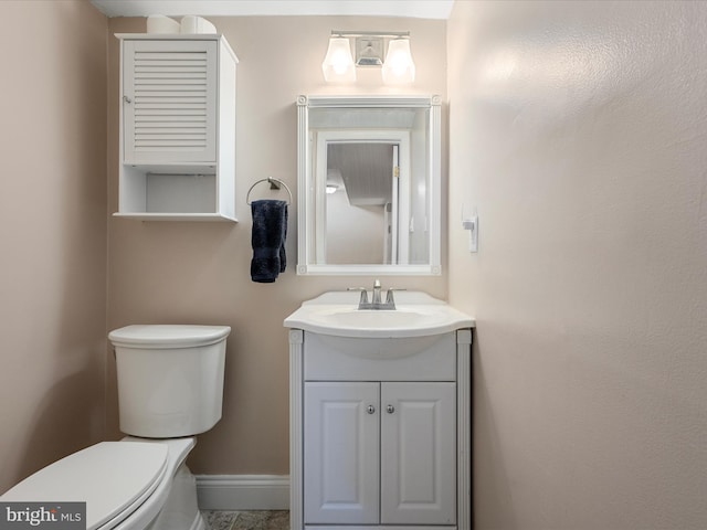 bathroom with baseboards, toilet, and vanity