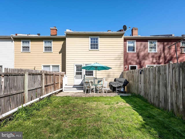 rear view of property featuring a fenced backyard, a chimney, and a yard