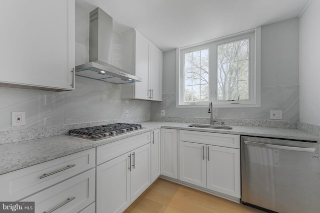 5634 6th St N, Arlington, VA 22205 - kitchen with stainless steel appliances, wall chimney range hood, a sink, white cabinetry, and light wood finished floors