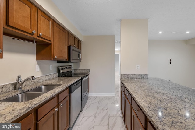 kitchen featuring appliances with stainless steel finishes, light stone countertops, marble finish floor, and a sink