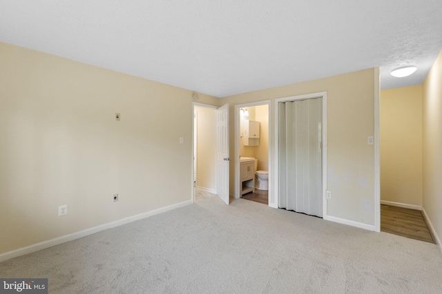 unfurnished bedroom with baseboards, ensuite bath, and carpet floors