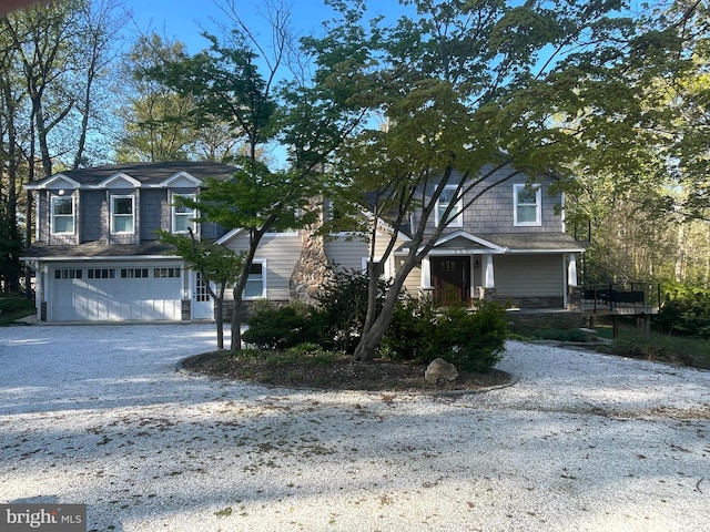 view of front of home featuring a garage, gravel driveway, and stone siding