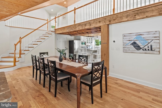 dining space featuring stairs, a towering ceiling, baseboards, recessed lighting, and light wood-style flooring