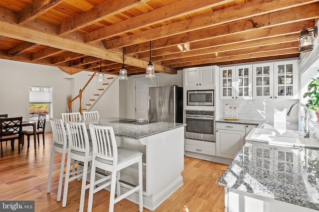 kitchen with beamed ceiling, a center island, wood ceiling, a sink, and stainless steel appliances