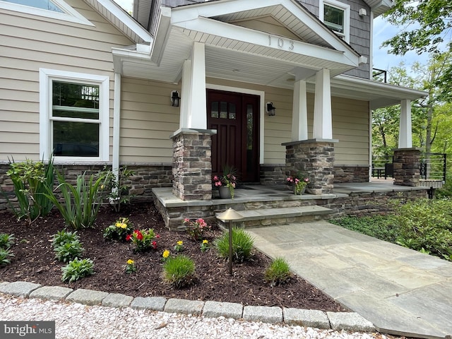 doorway to property featuring covered porch and stone siding