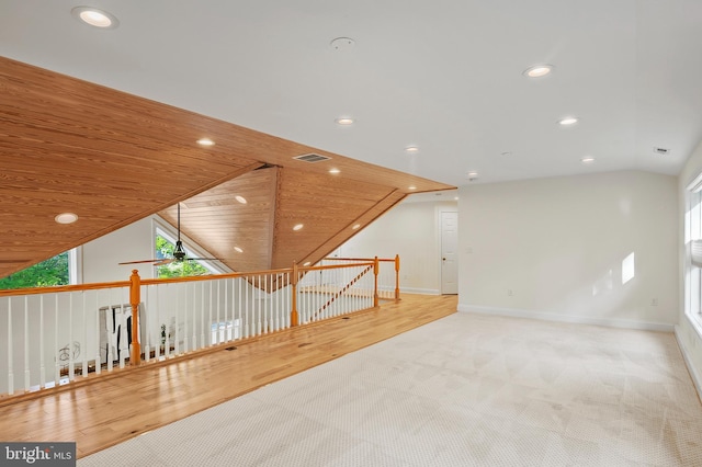 additional living space with visible vents, lofted ceiling, wood finished floors, baseboards, and recessed lighting