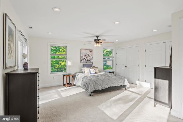 bedroom featuring recessed lighting, multiple closets, light colored carpet, and visible vents