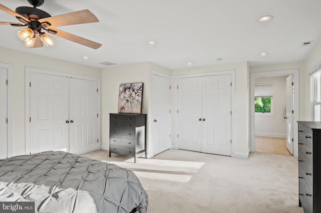 bedroom with multiple closets, light carpet, recessed lighting, and visible vents